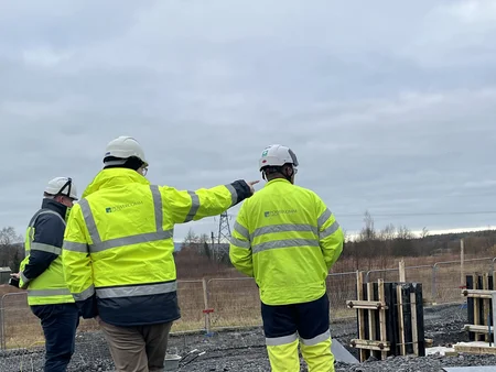 Three staff members wearing bright green PPE with the Powercomm logo on their backs standing onsite in Ballycore. 