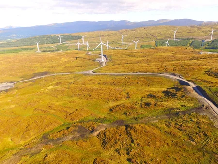 A drone image of Meenaward Windfarm, showcasing a vast field with scattered wind turbines.