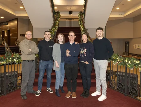 Six members of the Safety, Health, Environment, and Quality team stand on a landing in front of a staircase during Safety Day, December 2024.