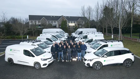 A fleet of cars lined up on the left and right, with a group of Powercomm staff members standing in the middle during December 2024.