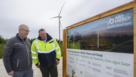 Martin Eager and James Cafferty standing next to sign and looking at the information displayed about Sheskin Wind Farm 