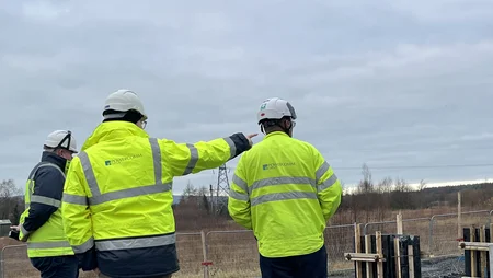 Three staff members wearing bright green PPE with the Powercomm logo on their backs standing onsite in Ballycore. 