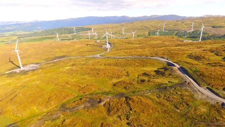 A drone image of Meenaward Windfarm, showcasing a vast field with scattered wind turbines.